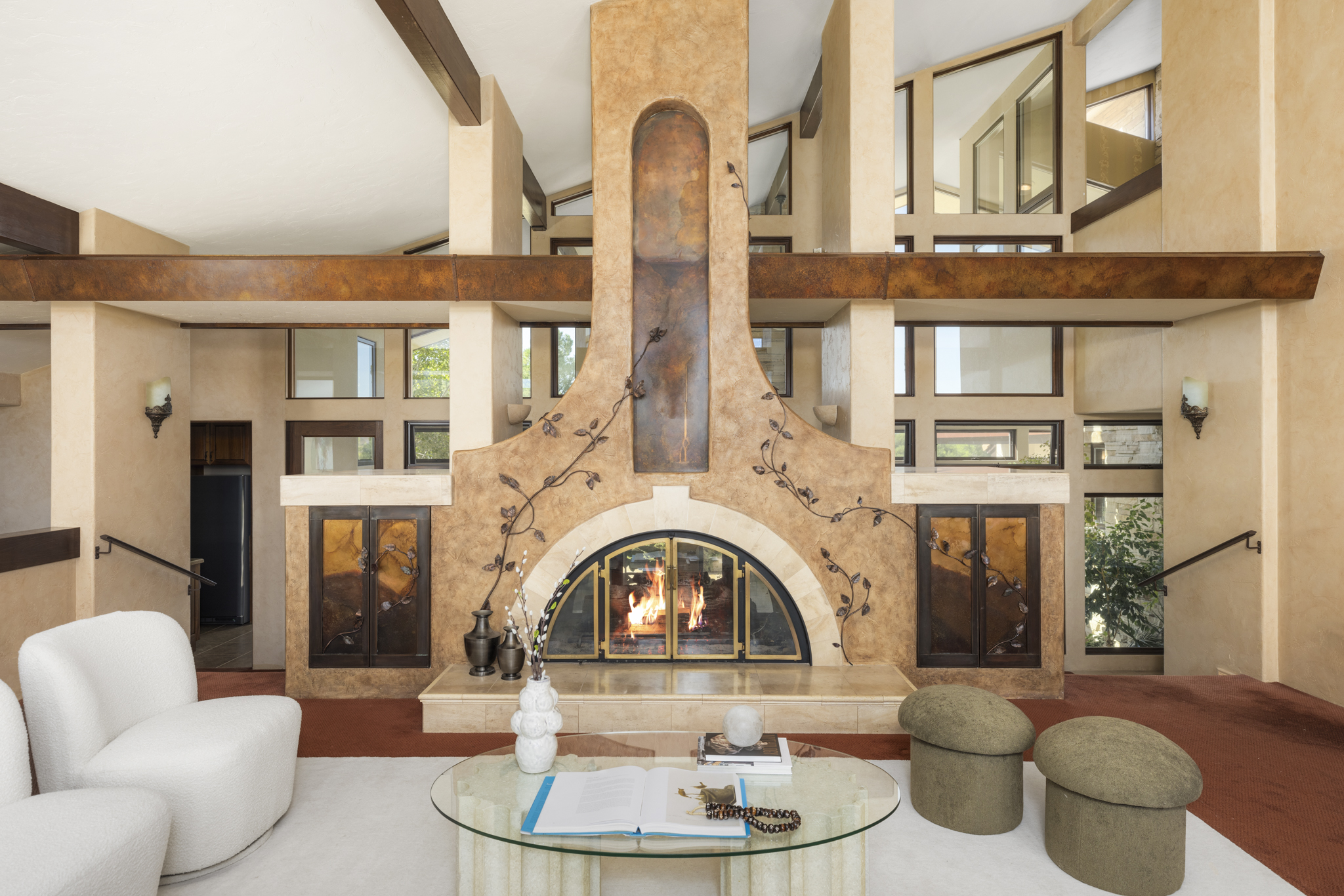 Living room with sculptural stone fireplace beneath cathedral ceilings and towering windows
