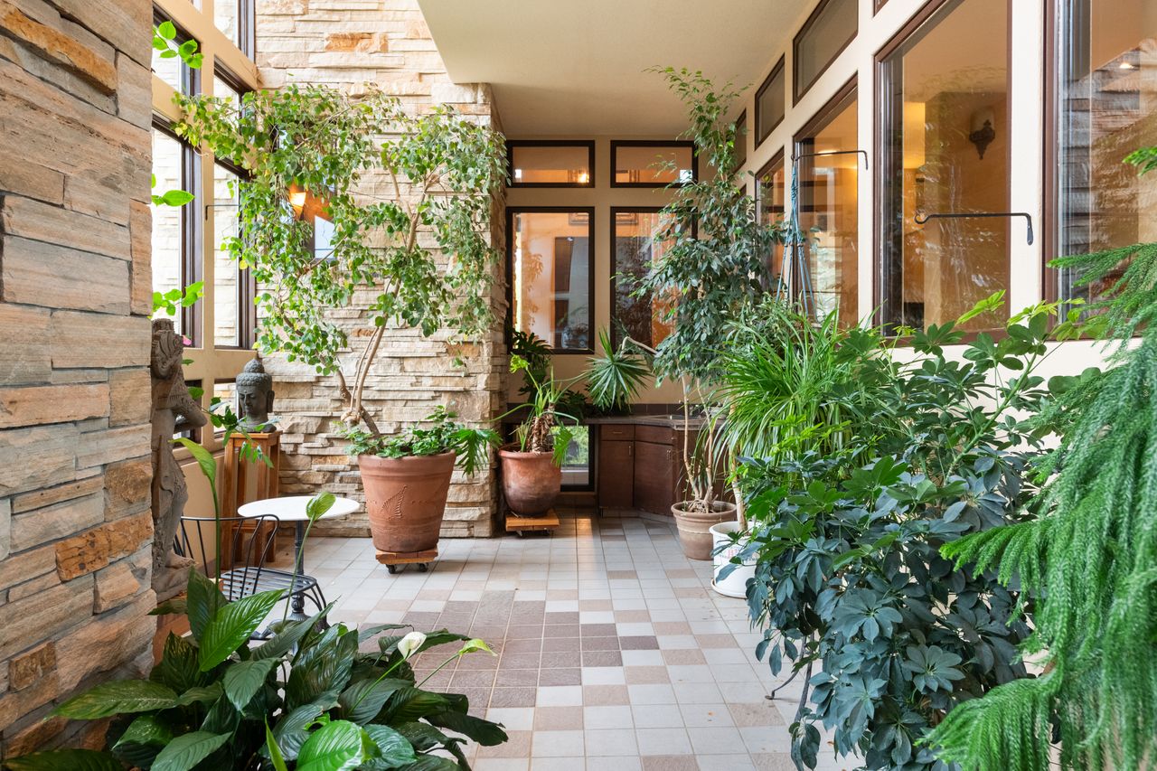 Glass atrium with plants and stone wall